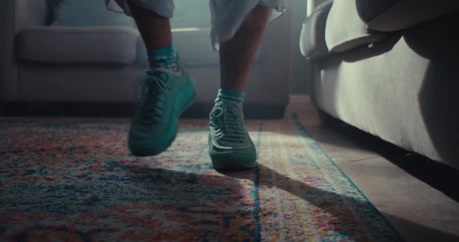 Feet of a person wearing blue sneakers walking on a carpet