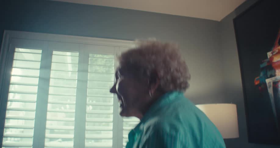 Elderly woman dancing and smiling in a sunlit living room