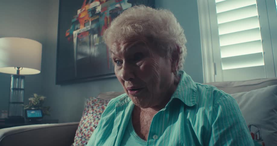 Elderly woman with surprised expression sitting on a sofa in the living room