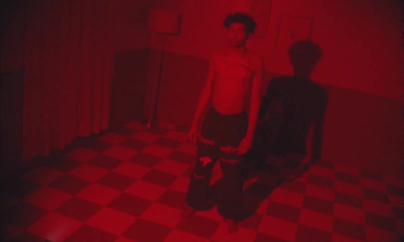 A boy stands in a dark room with flickering lights