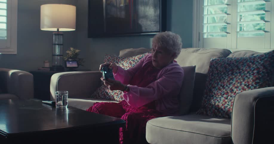Elderly woman is playing video games in a living room