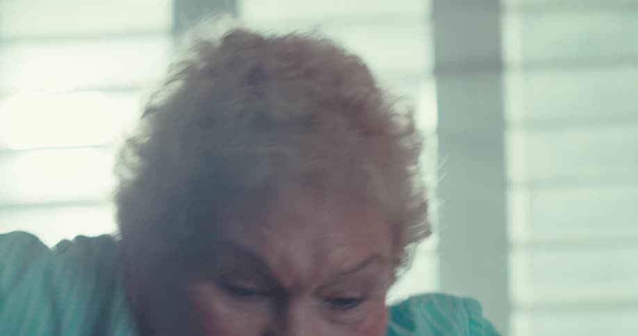 Elderly woman smiles while dancing in her living room alone during the daytime