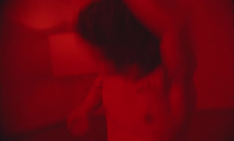 The man is dancing in the room under a red light