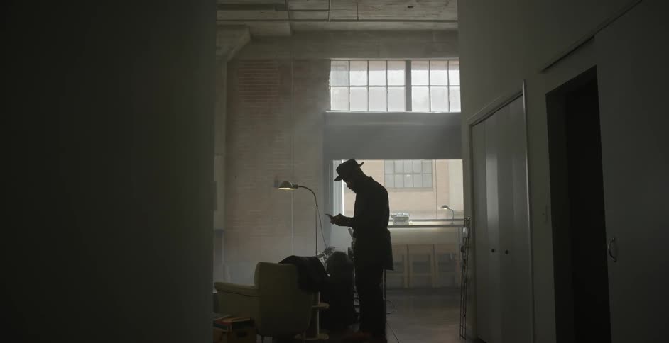 A man takes a drink, checks device, grabs coat and leaves