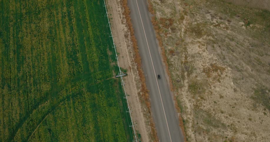 A lone car drives a long empty road