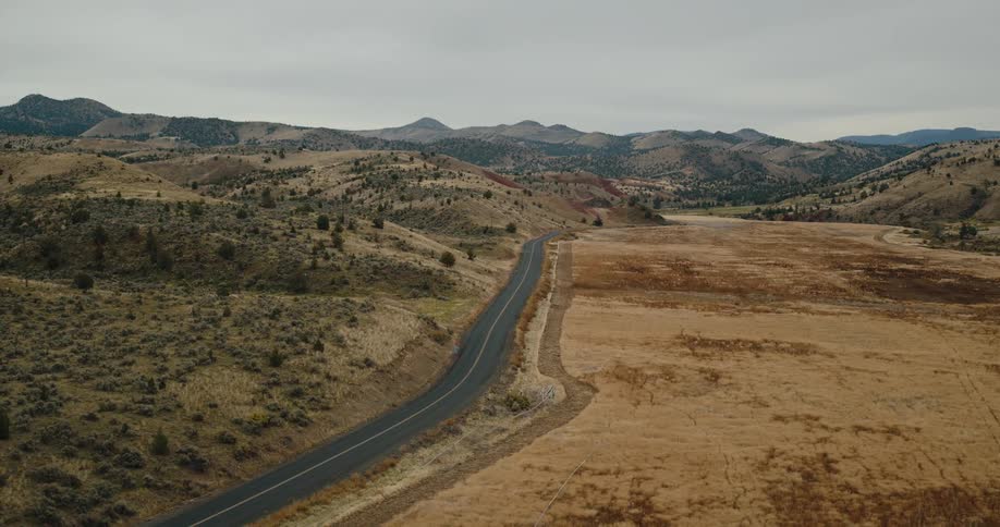 Aerial view of a winding desert highway through the hills on a cloudy day