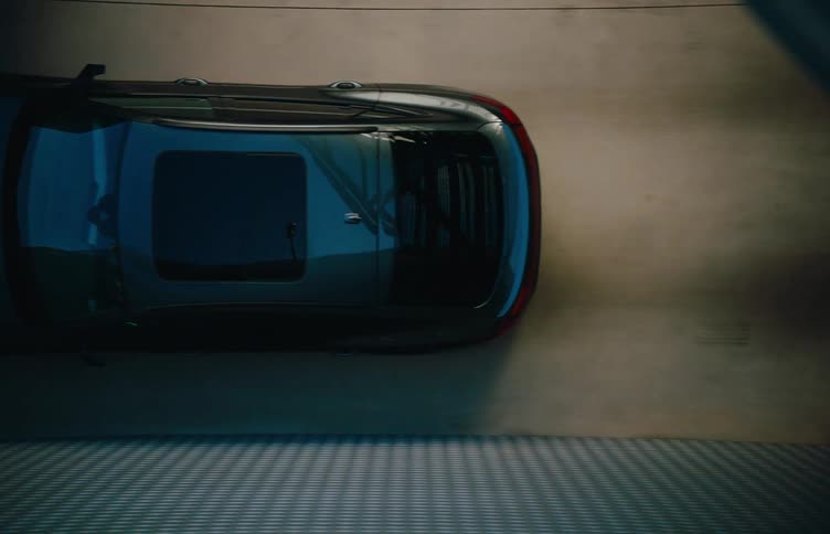 A car drives past a steel bridge at midday