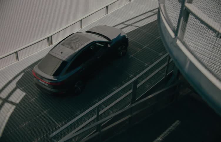 Black car driving up a spiral ramp in a parking structure
