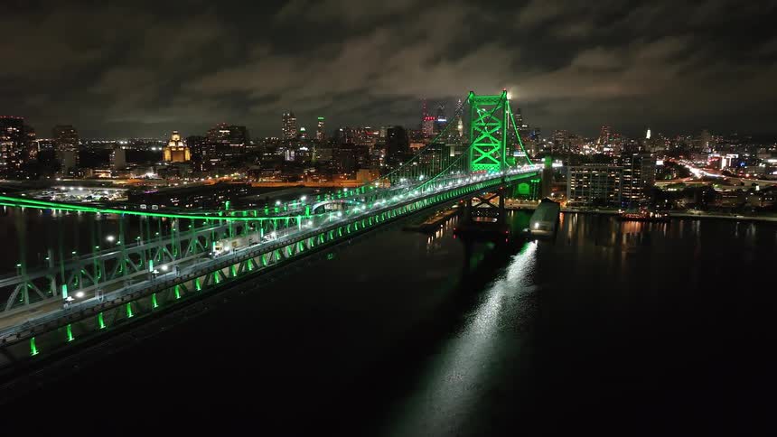 Aerial view of Benjamin Franklin Bridge lit up at night with the Philadelphia skyline in the background