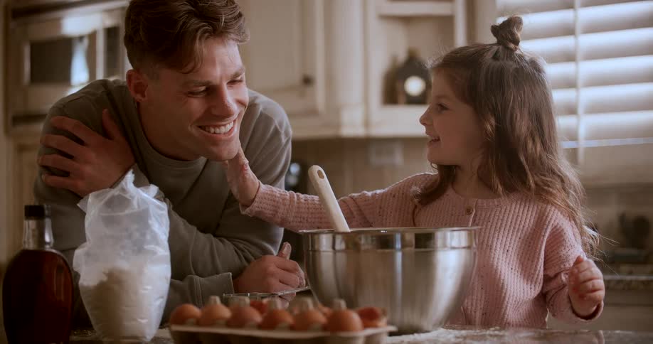A daughter wipes flour on her fathers face