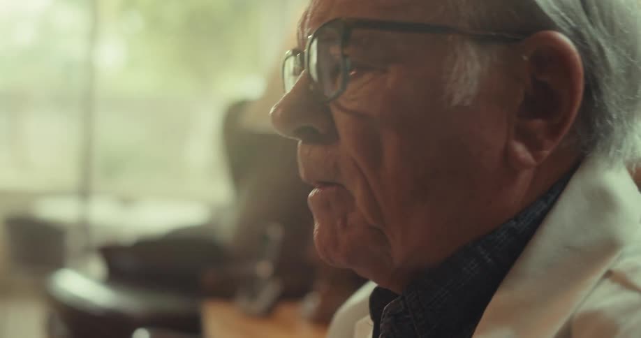 A doctor wearing glasses sits and explains something to another person