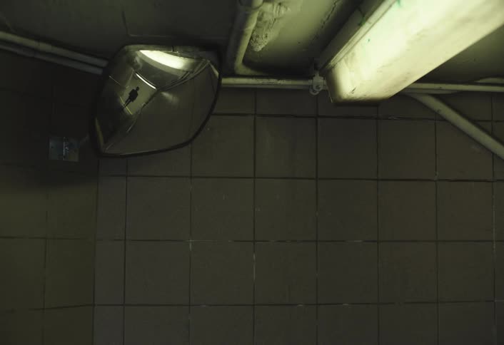 A mirror in the corner of a wall reflecting the image of a person who passed in front of it