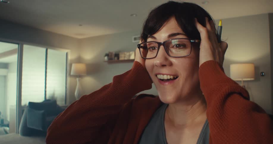 A woman smiles and touches her head