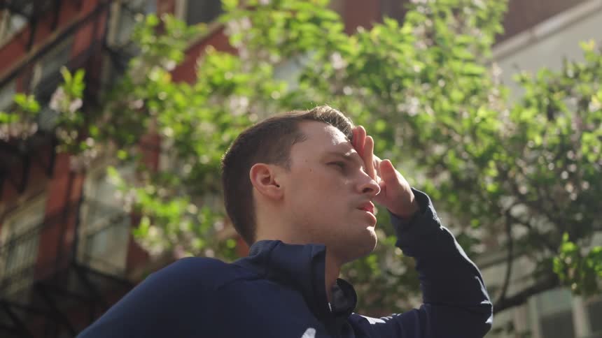Man placing hand on face while standing outdoors