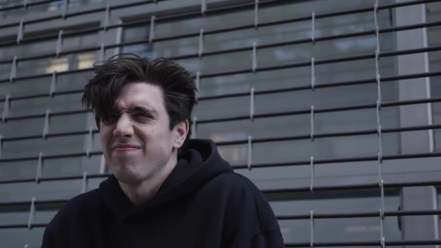 Man outdoors with a black hoodie and his hair flying in the wind
