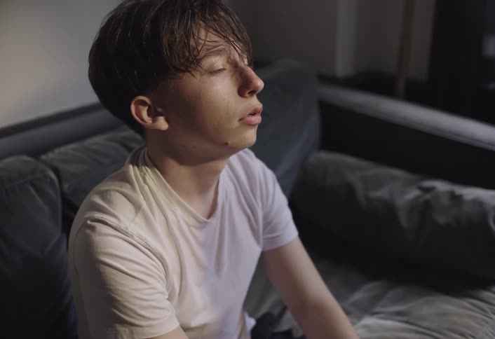 Boy sitting in armchair raising and lowering his head