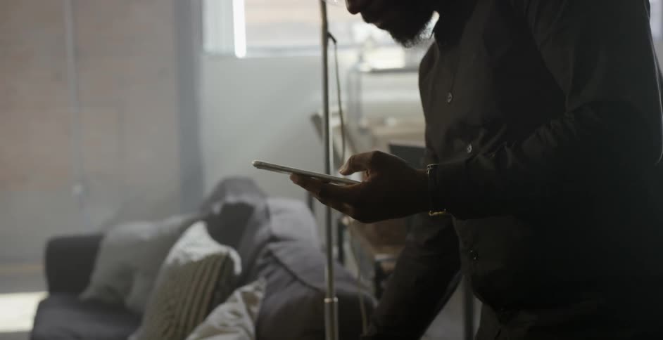 Man drinks from glass then begins using his electronic device