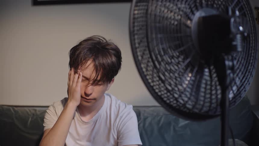 The fan is blowing on a hot man