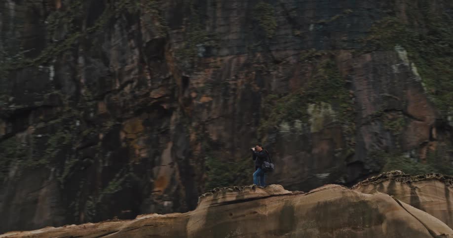 Person with a camera on top of a rocky mountain