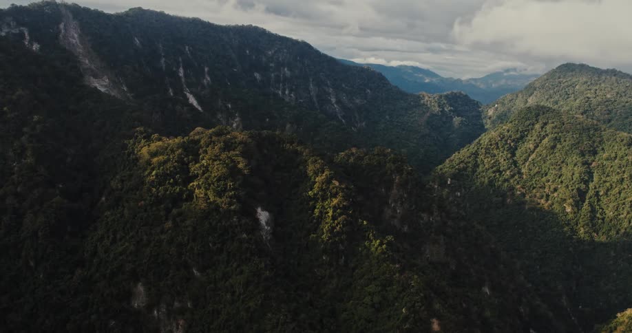 Lush green mountains and forested canyon under a cloudy sky
