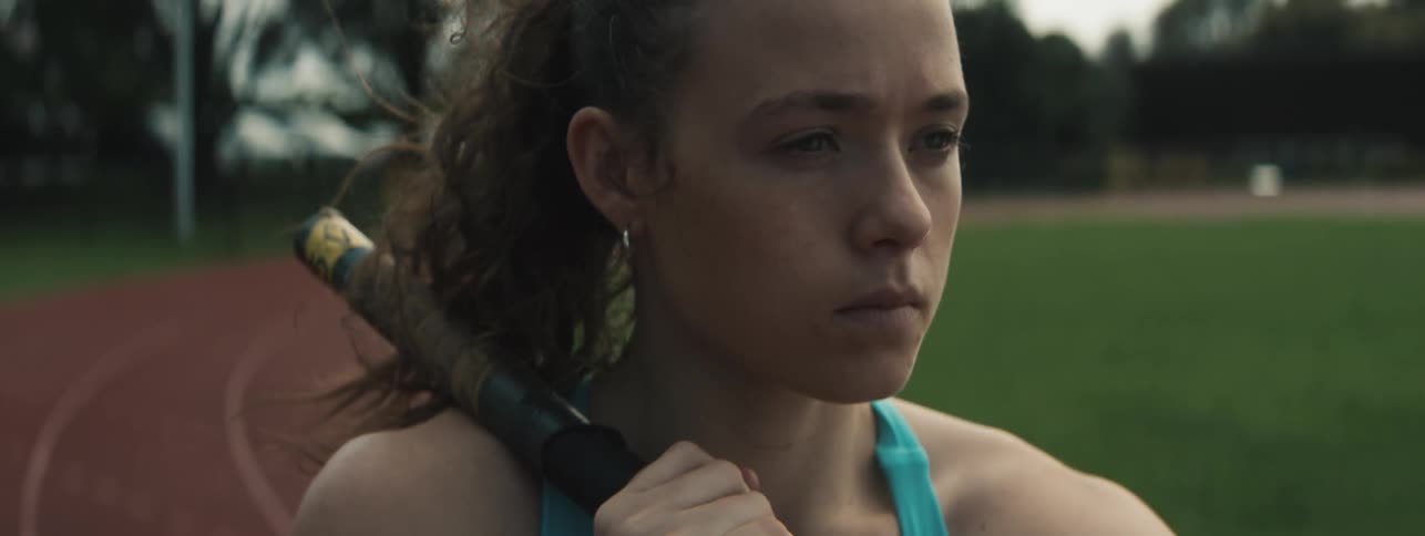 Teenage female pole vaulter adjusts her vaulting pole before starting her run on a summer day
