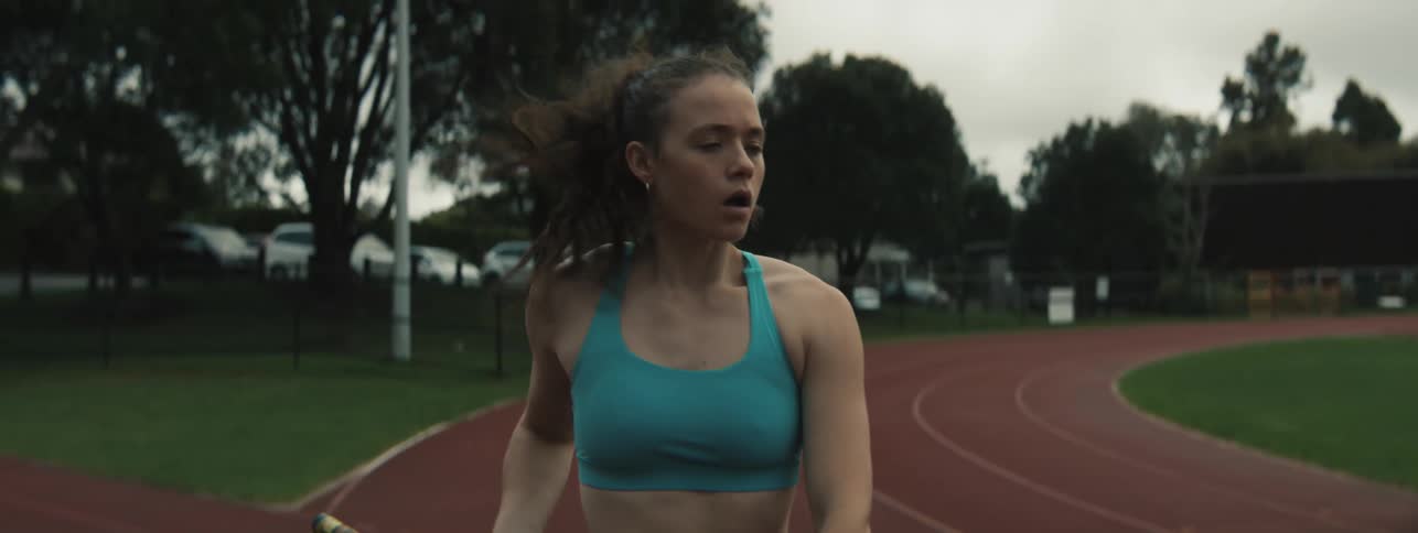 Athlete prepares for pole vault on outdoor athletics track under cloudy sky
