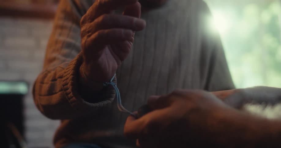 A man ties a virtual reality controller to an elderly mans wrist with an attached string
