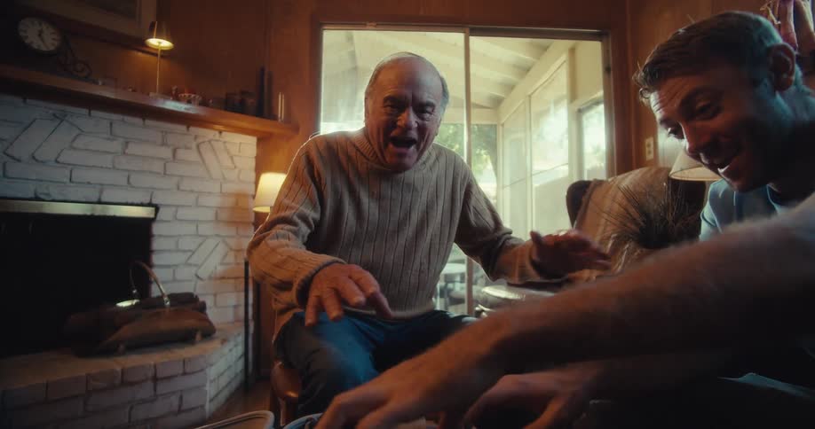 Young man presenting a device to an elderly man who is surprised and happy