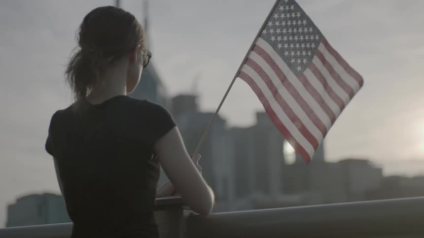 A woman is holding a flag overlooking a city