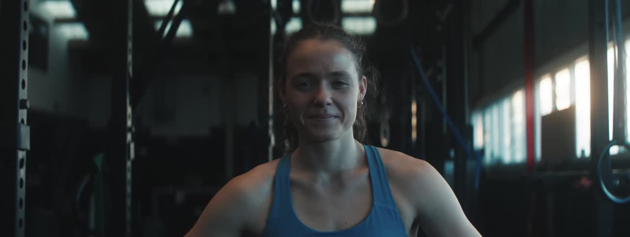 Young woman smiles while standing inthe gym during the daytime