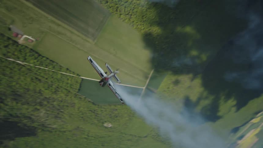 Plane releasing smoke and performing radical aerial maneuvers