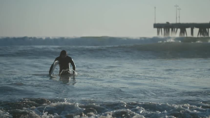 A surfer walking in ocean waves