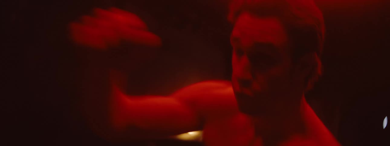 The man is shadowboxing under a red light