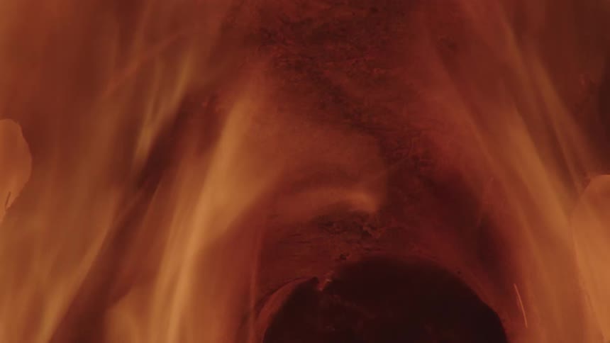 Fire roars in a rough container with multiple openings