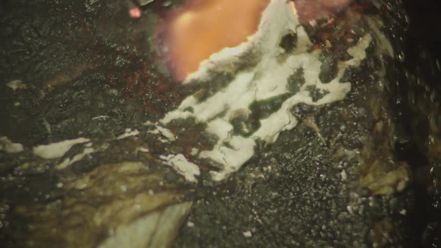 Orange flame burns on the surface of a cooking piece of meat