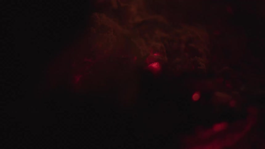 Glowing embers and ash swirl in a darkened space suggesting the remnants of a fire