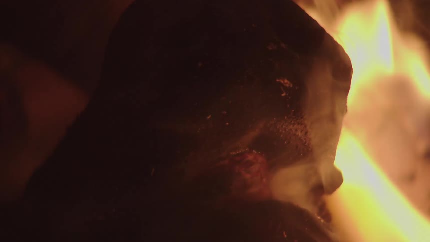 Close up of a pig being roasted on coals and fire