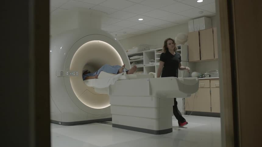 A nurse walks away as the patient moves into the mri machine