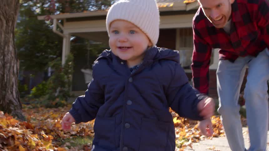 A man running after a small child playing in front of a house