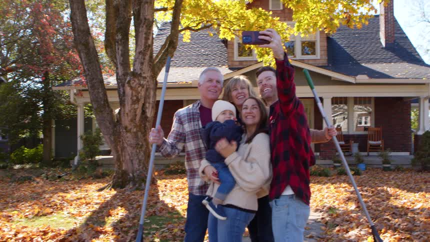 Cheerful family taking selfie in the backyard and a house with dry leaves