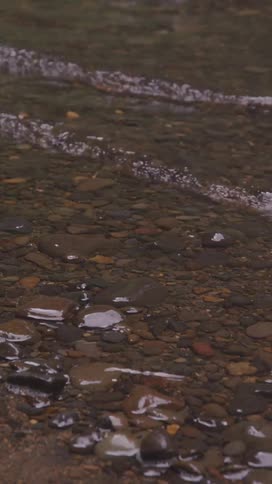 A rocky riverbank with gentle waves hitting the shore at midday