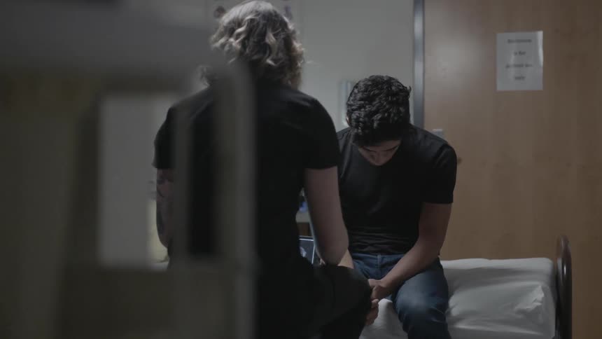 Two men sitting on a bed talking