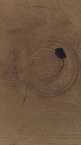 Aerial of a vehicle driven in circles in the desert during daytime