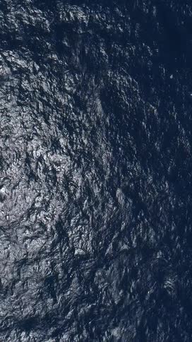 The calm ocean water has ripples caused by a light wind at midday
