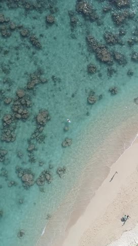 A person is sitting on a surfboard by the shore