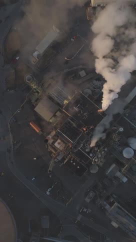 Smoke rises from multiple chimneys at a factory creating an obscuring haze