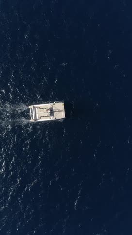 A sailboat glides across the calm ocean at midday