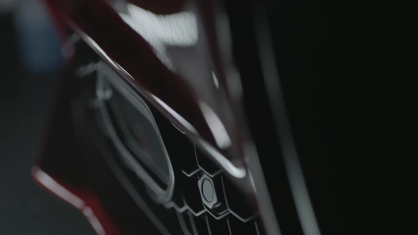 The grill of an automobile reflects light and shadow