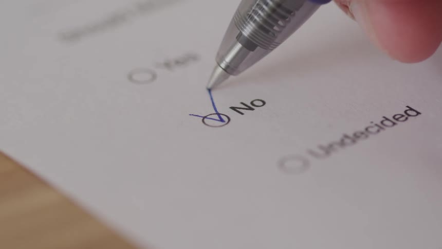 Close up of an answer sheet as a person ticks an option with a pen