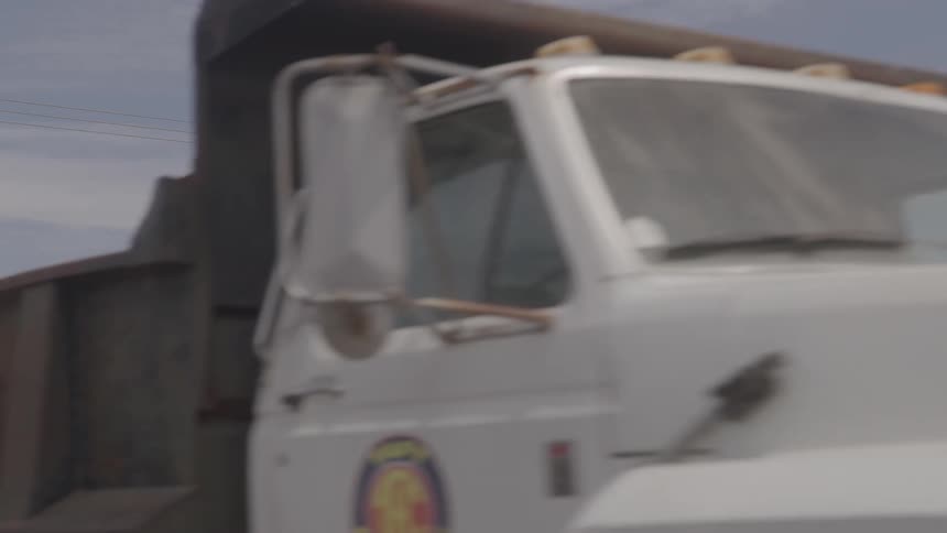 Dump truck driving along an urban road with the us flag in the background